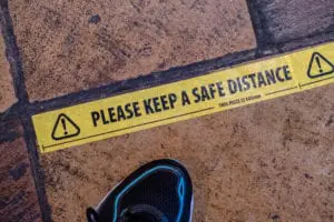 A shoe next to yellow tape on the floor of a pub to ensure that customers maintain social distancing