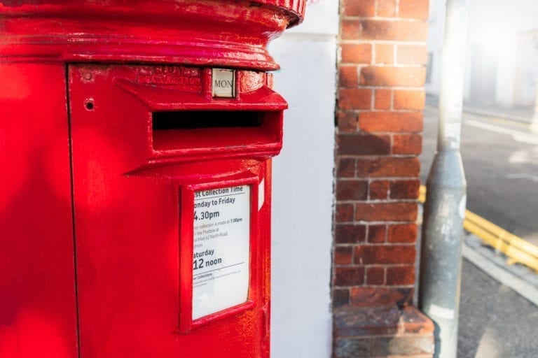 Close-up view of a old traditional vintage classic red letter box or postbox standing on sidewalk