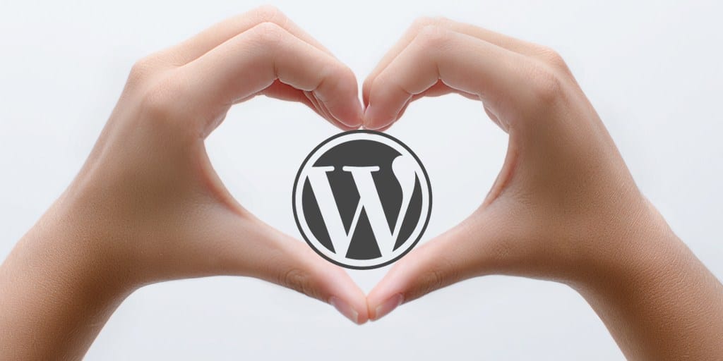 two hand making a heart image with a wordPress logo inside