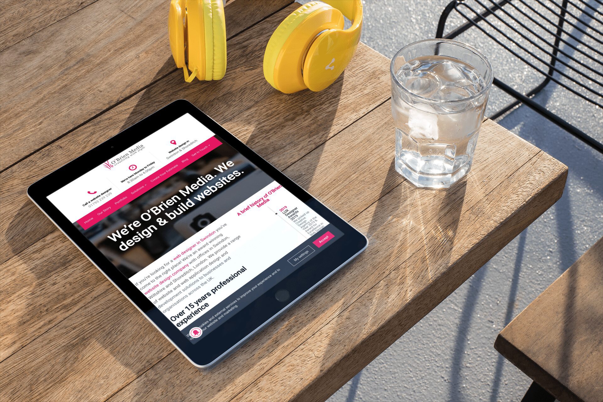 a glass of water by a tablet displaying OBrien Media website