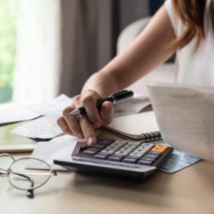 Stressed young woman checking bills, taxes, bank account balance and calculating expenses in the living room at home