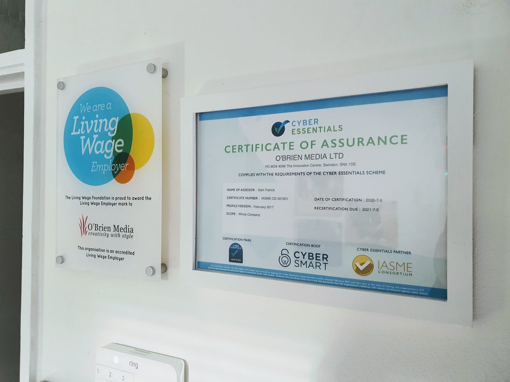certificates of living wage and cyber essentials on a white wall