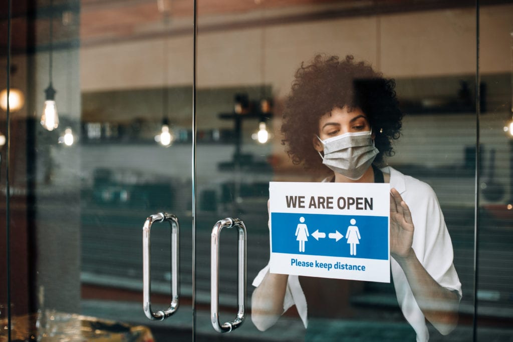 Coffee shop female owner with protective face mask, reopens