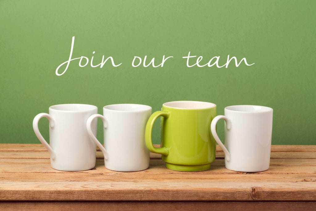 Four mugs on a table with one green mug standing out, and the text ‘Join our team’ above
