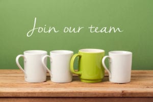 Four mugs on a table with one green mug standing out, and the text ‘Join our team’ above