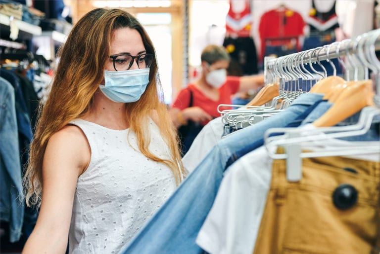 Woman in a safety mask looking at clothes in a shop