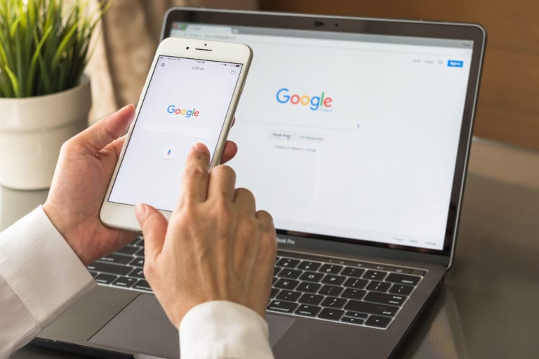 Google search engine sign up page on mobile app touchscreen on iphone in business person's hand and on computer screen display