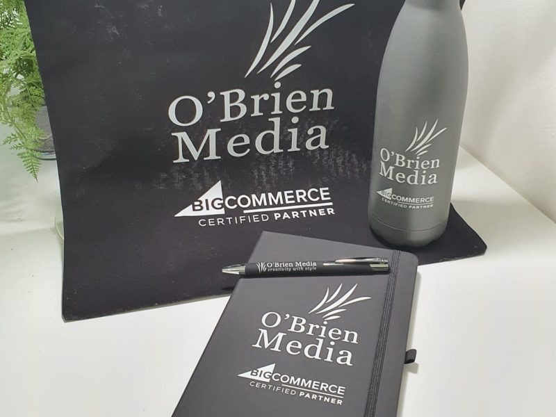 a pen, a bottle and notebook with OBrien Media logo