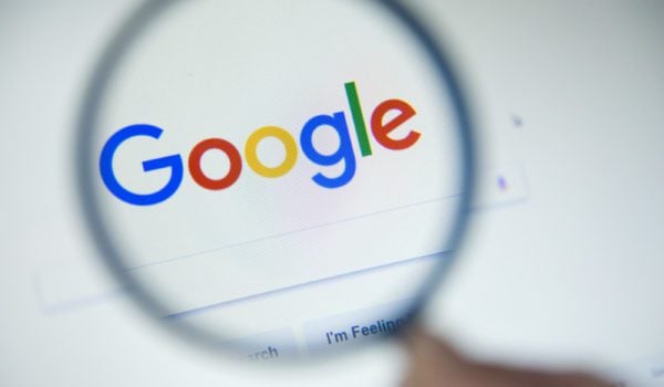 Google homepage on the screen under a magnifying glass.