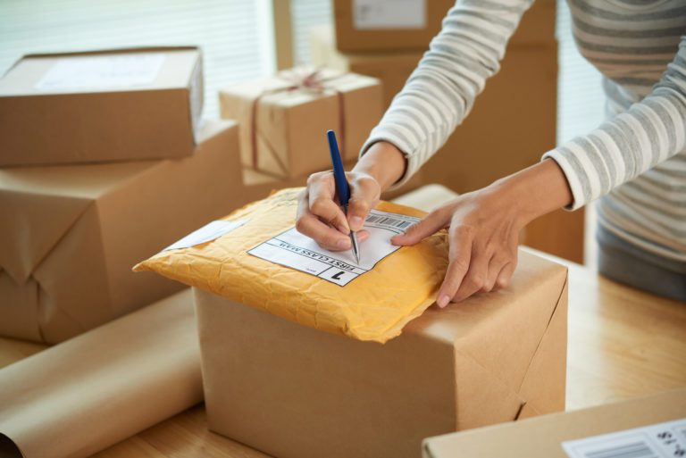 A woman writting address in a parcel