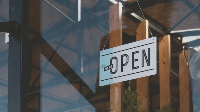 CU we are open sign hanging on the entrance door of a small cafe