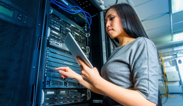 Young engineer businesswoman with tablet in network server room