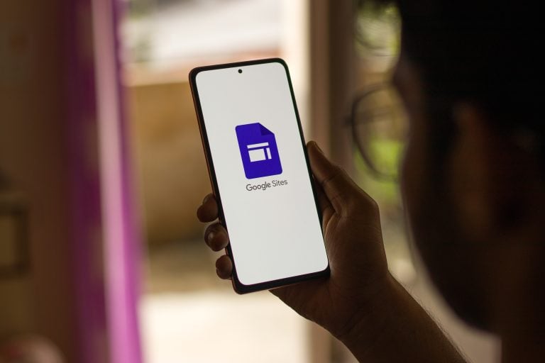 Person holding a smartphone displaying the Google Sites logo on screen
