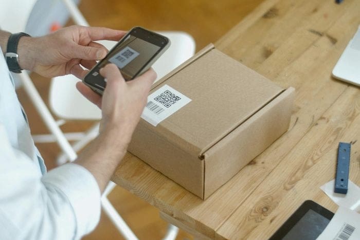 Person scanning a QR code from a laptop screen using a smartphone