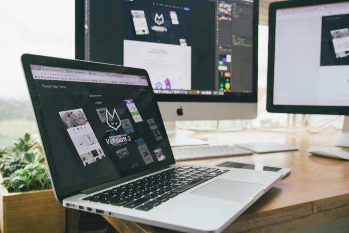 Laptop on a desk with website design wireframes and planning notes