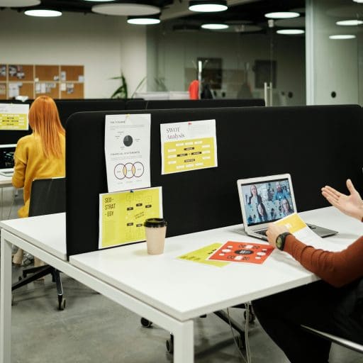 People working on laptops in a modern open-plan office with white desks