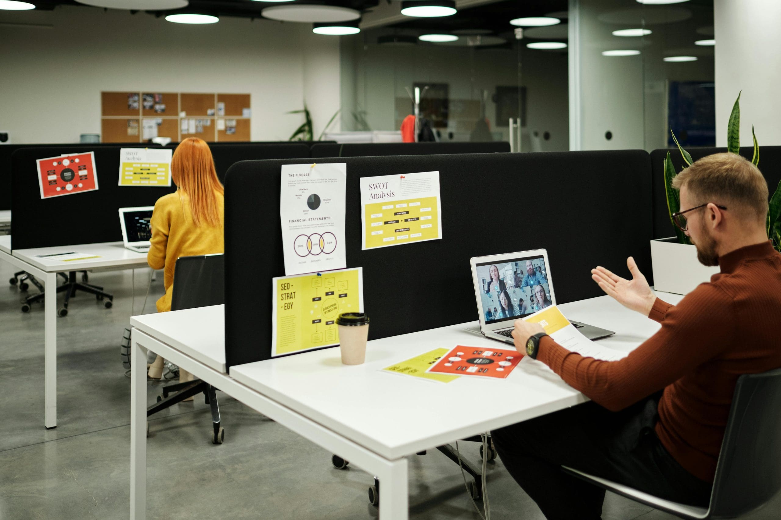 People in a modern office sat at white desks using laptops