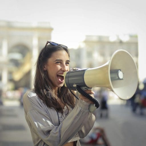 Woman shouting into a megaphone in a sunny street to promote summer website optimisation