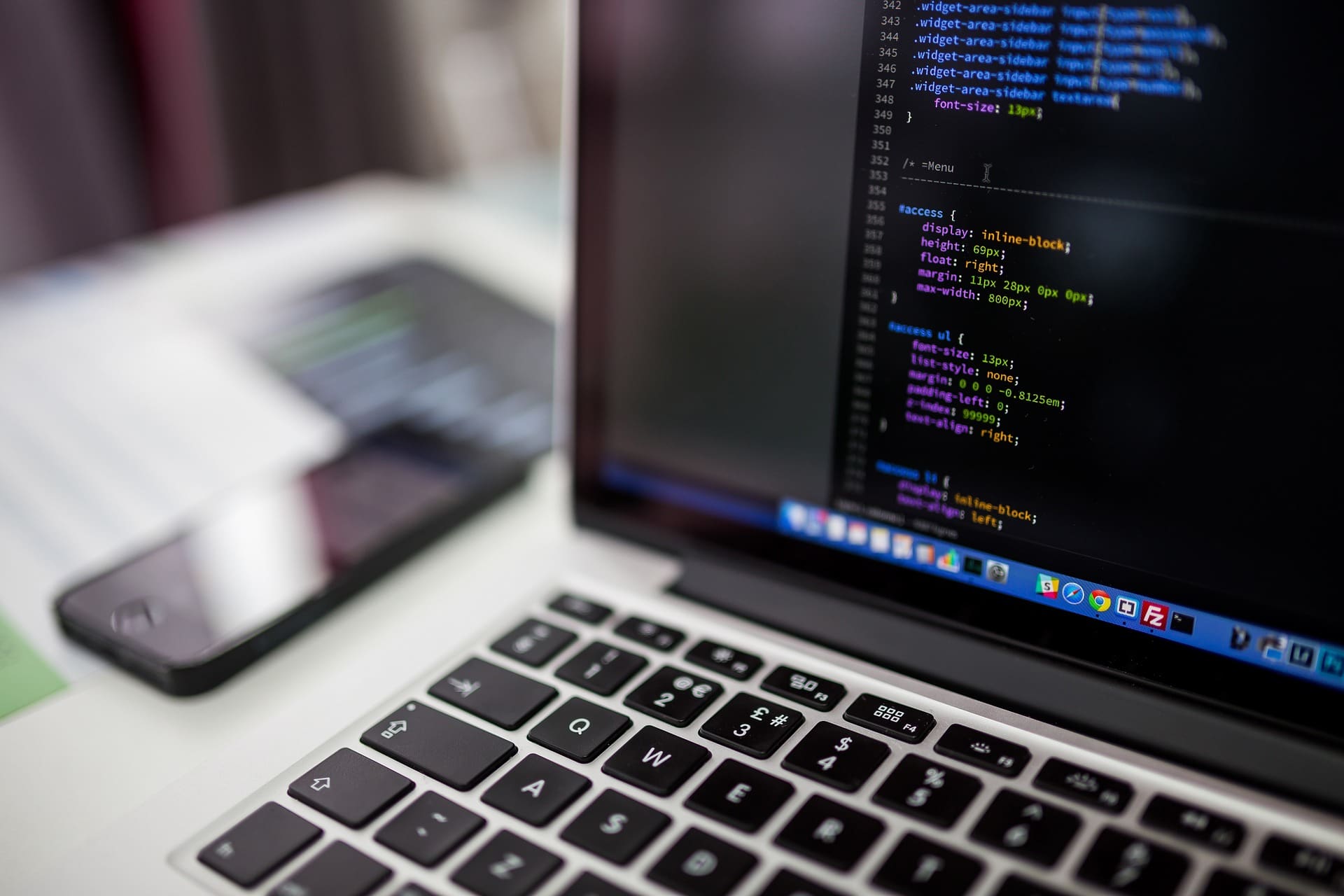 Macbook laptop on a desk in an office showing code on the screen